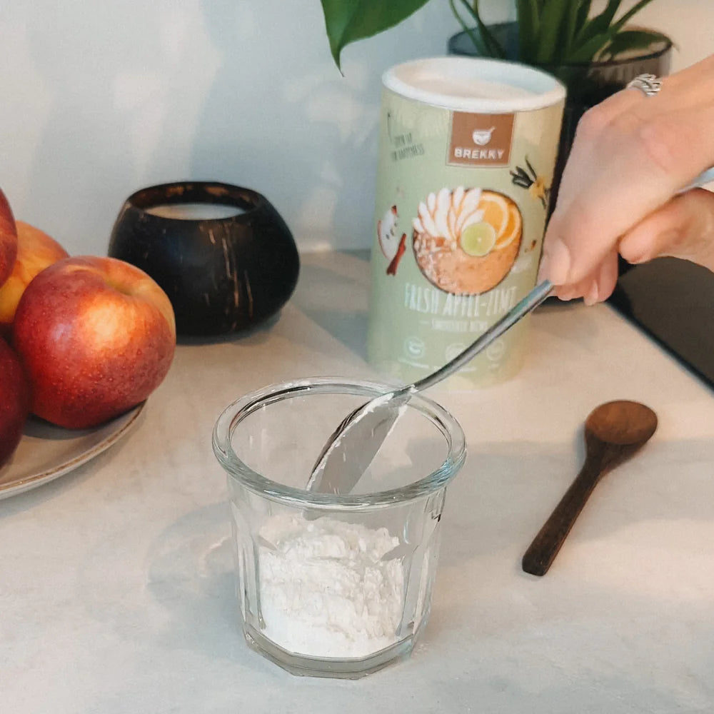 Pulver wird in Glas gelöffelt neben Apfel-Zimt Dose