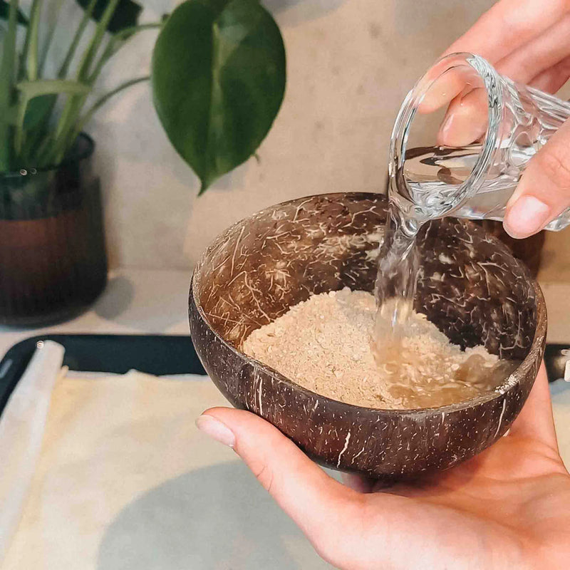 Wasser wird in Kokosschale mit Porridge gegossen