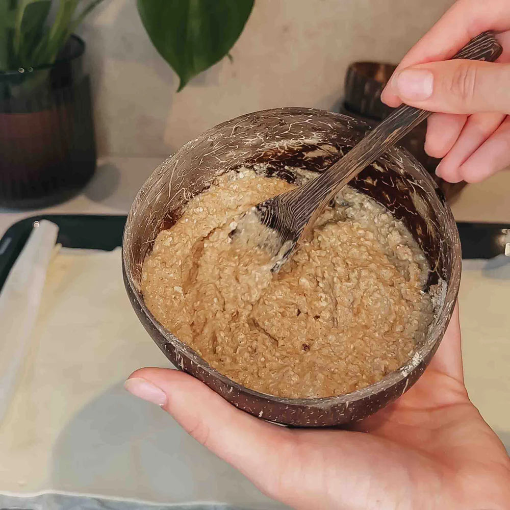 Hände rühren Teig in Kokosschale