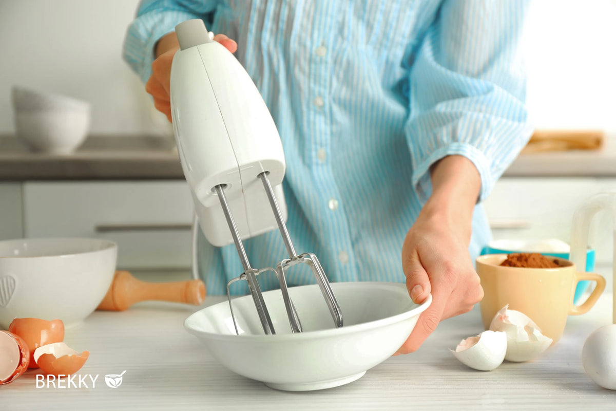 Frau rührt mit Handmixer in Schüssel