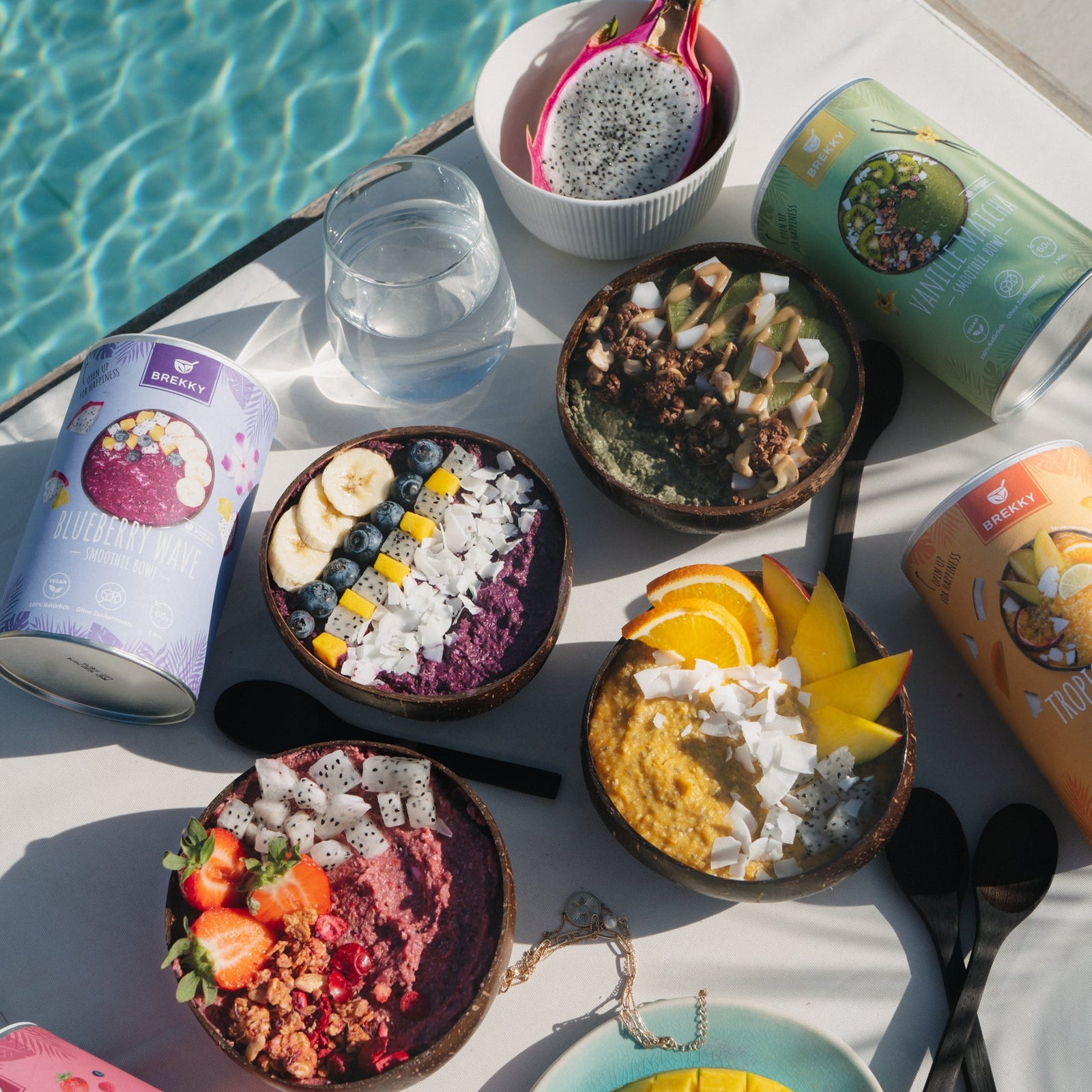 Mehrere Smoothie Bowls und Dosen am Pool